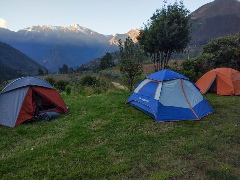 Tres carpas en el pasto del jardín, con el nevado Padreyoc al fondo en la primera luz