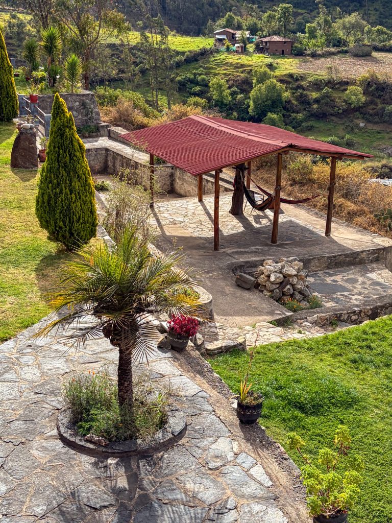 El jardín delante de la casa, plano y con pasto, junto al muro de piedra